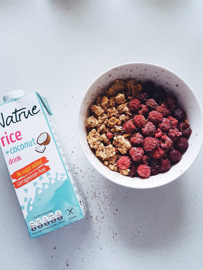 services-01 A bowl of fresh raspberries and granola paired with rice coconut milk for a healthy breakfast.