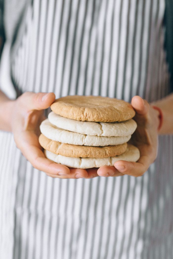 services-img Close-up of hands holding a stack of freshly baked bread against a striped apron.