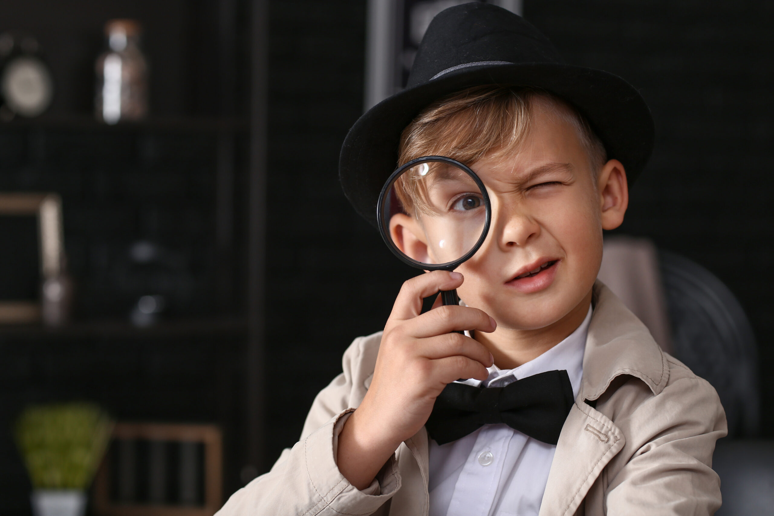 cute little detective with magnifying glass indoors