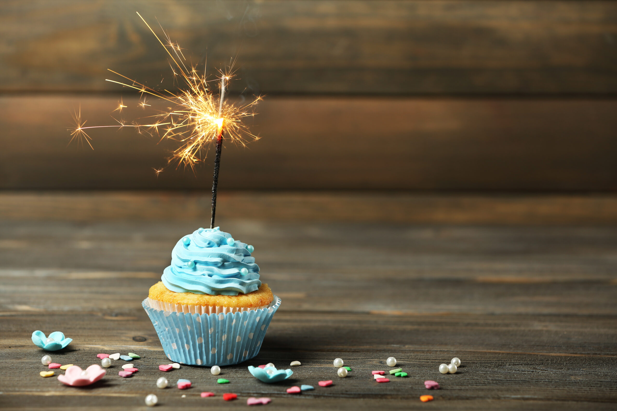 cupcake with sparkler on table on wooden background